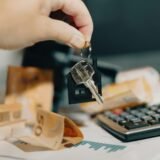 A person holding a house key in front of a calculator